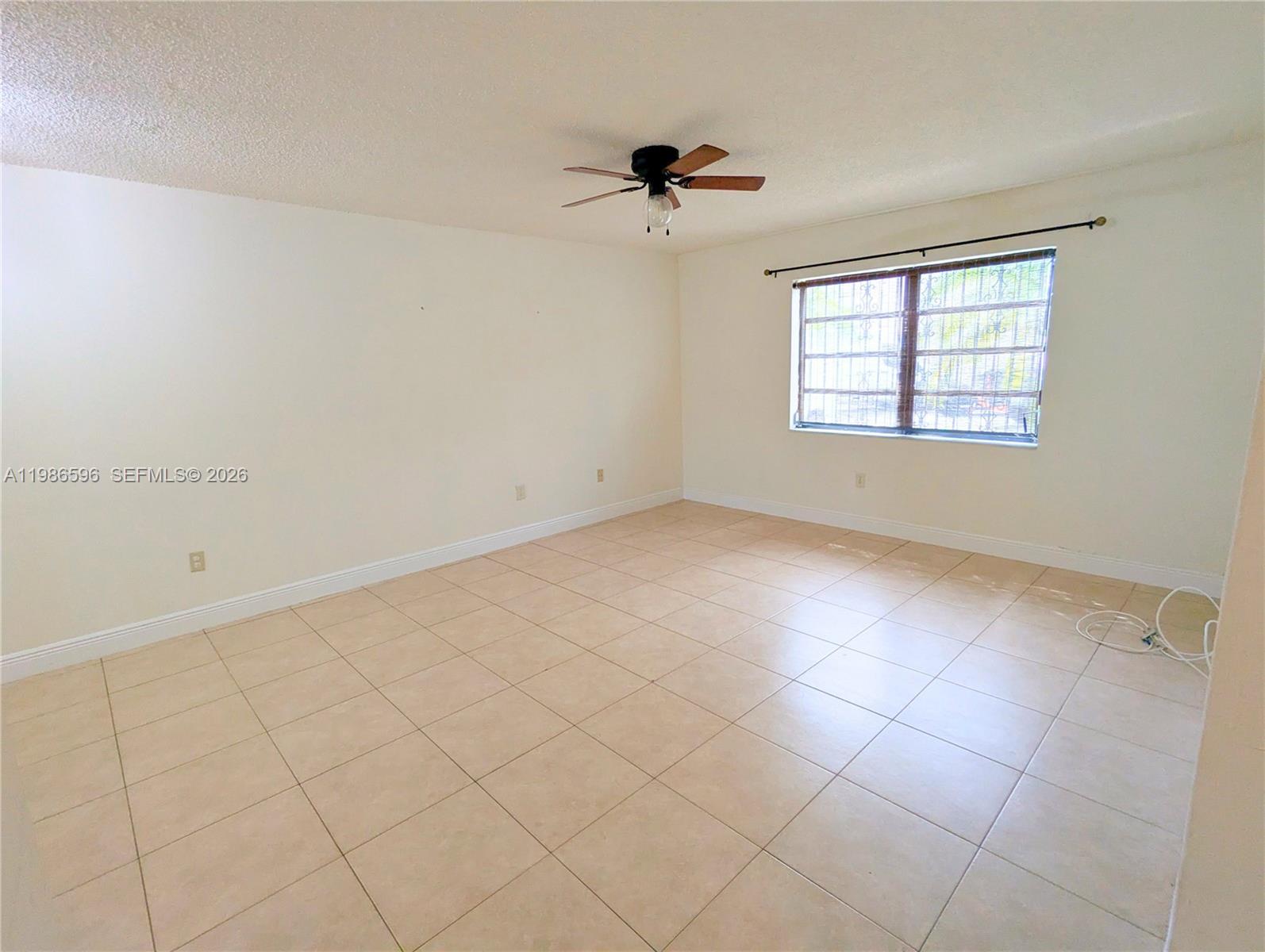 An empty room features beige tile flooring, white walls, and a ceiling fan — 4050 NW 135th St # 9, Opa-Locka FL 33054, OPA-LOCKA, FL
