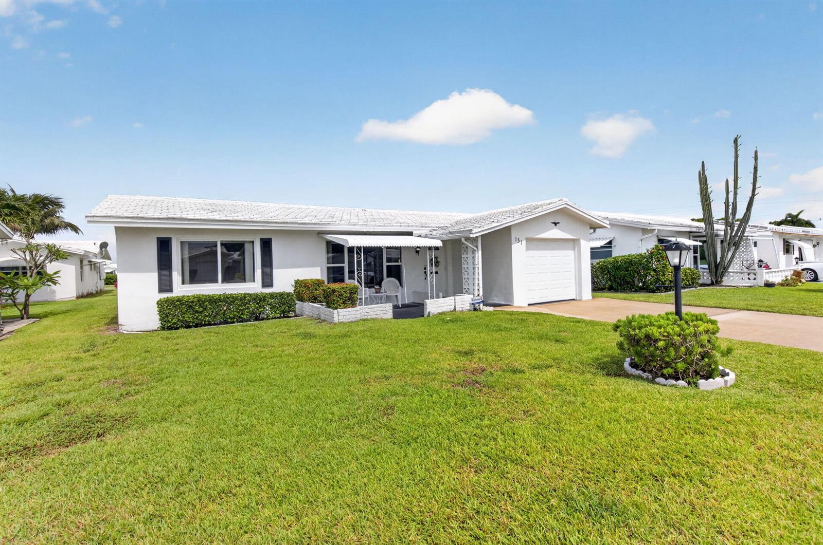 A single-story white house with a garage, a front lawn, and a small porch — 131 Leisureville Boulevard, Boynton Beach FL 33426, BOYNTON BEACH, FL
