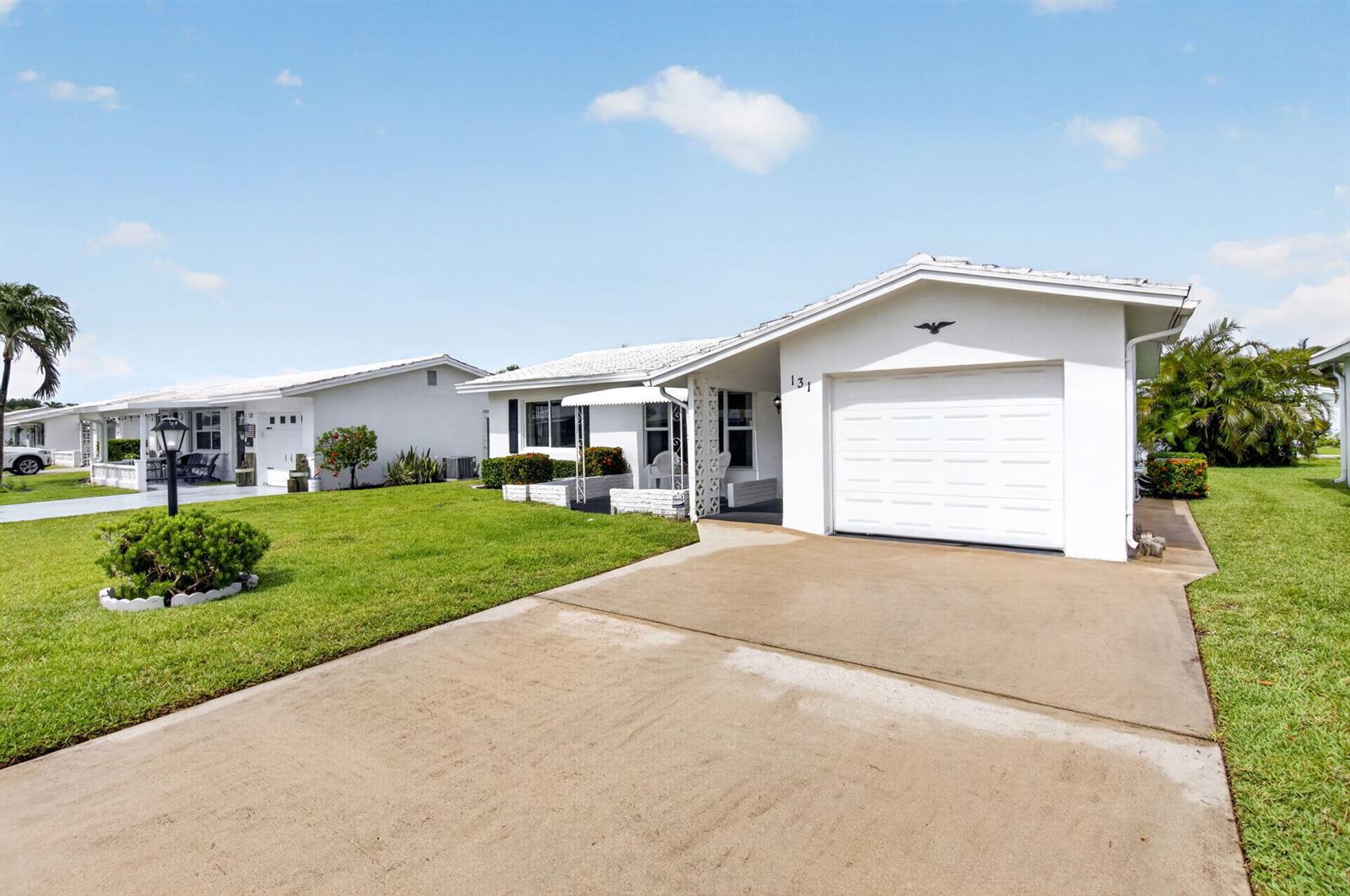 A white single-story house with a garage and a concrete driveway under a blue sky — 131 Leisureville Boulevard, Boynton Beach FL 33426, BOYNTON BEACH, FL