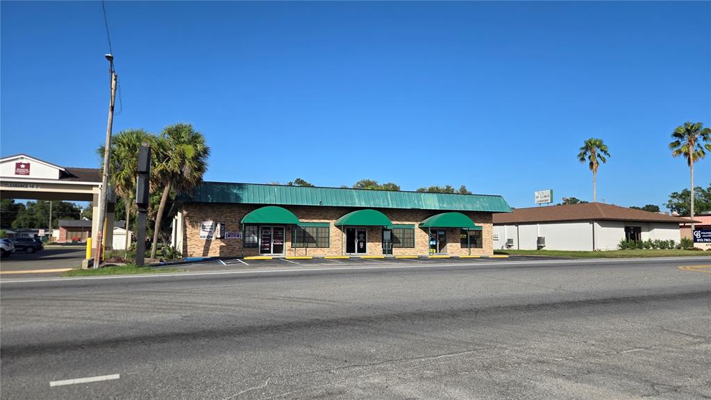 A single-story commercial building with a green metal roof and three green fabric awnings — 5720 GALL BOULEVARD UNIT 2, ZEPHYRHILLS, FL