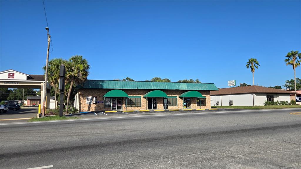 A single-story commercial building with a green metal roof and three green fabric awnings — 5720 GALL BOULEVARD UNIT 2, ZEPHYRHILLS, FL