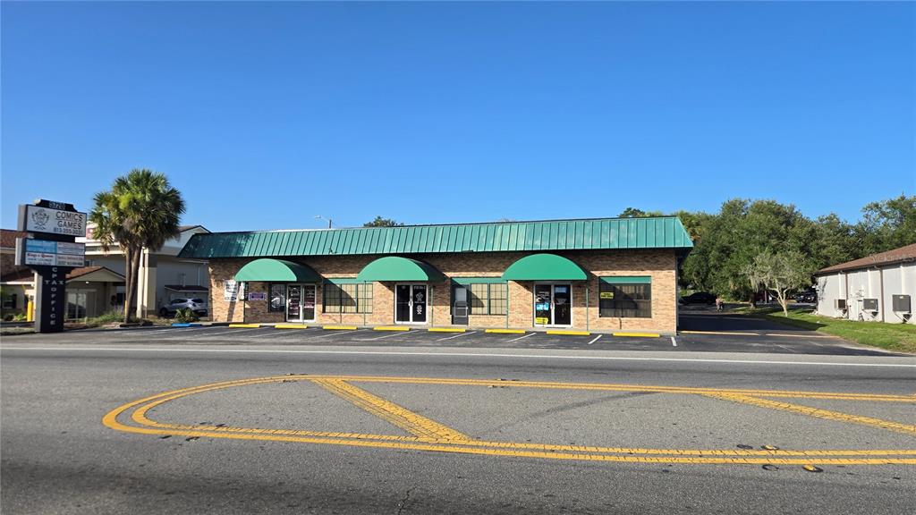 A single-story brick commercial building with a green metal roof and matching awnings — 5720 GALL BOULEVARD UNIT 2, ZEPHYRHILLS, FL