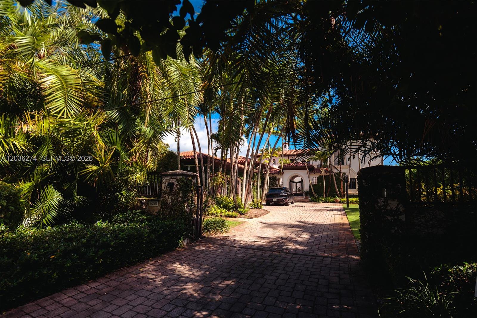 A paved driveway leads to a Mediterranean-style house surrounded by lush palm trees — 6220 SW 86th St # 0, Miami FL 33143, MIAMI, FL
