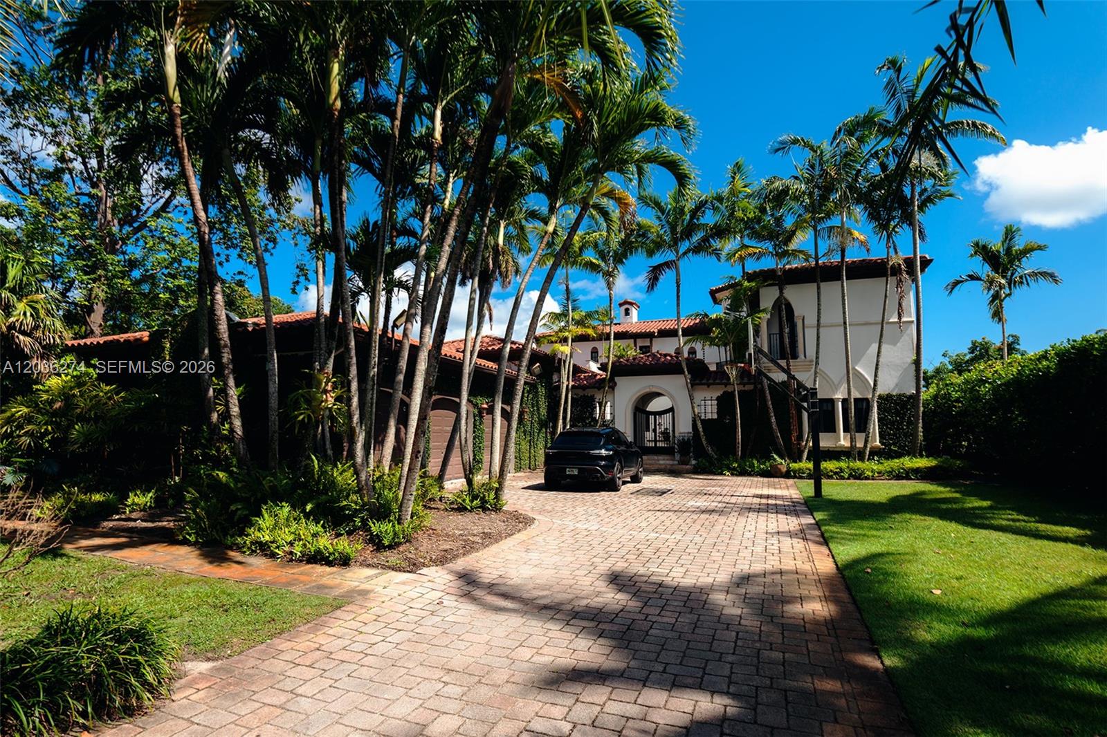 A large Mediterranean-style house with a paved driveway and palm trees under a blue sky — 6220 SW 86th St # 0, Miami FL 33143, MIAMI, FL