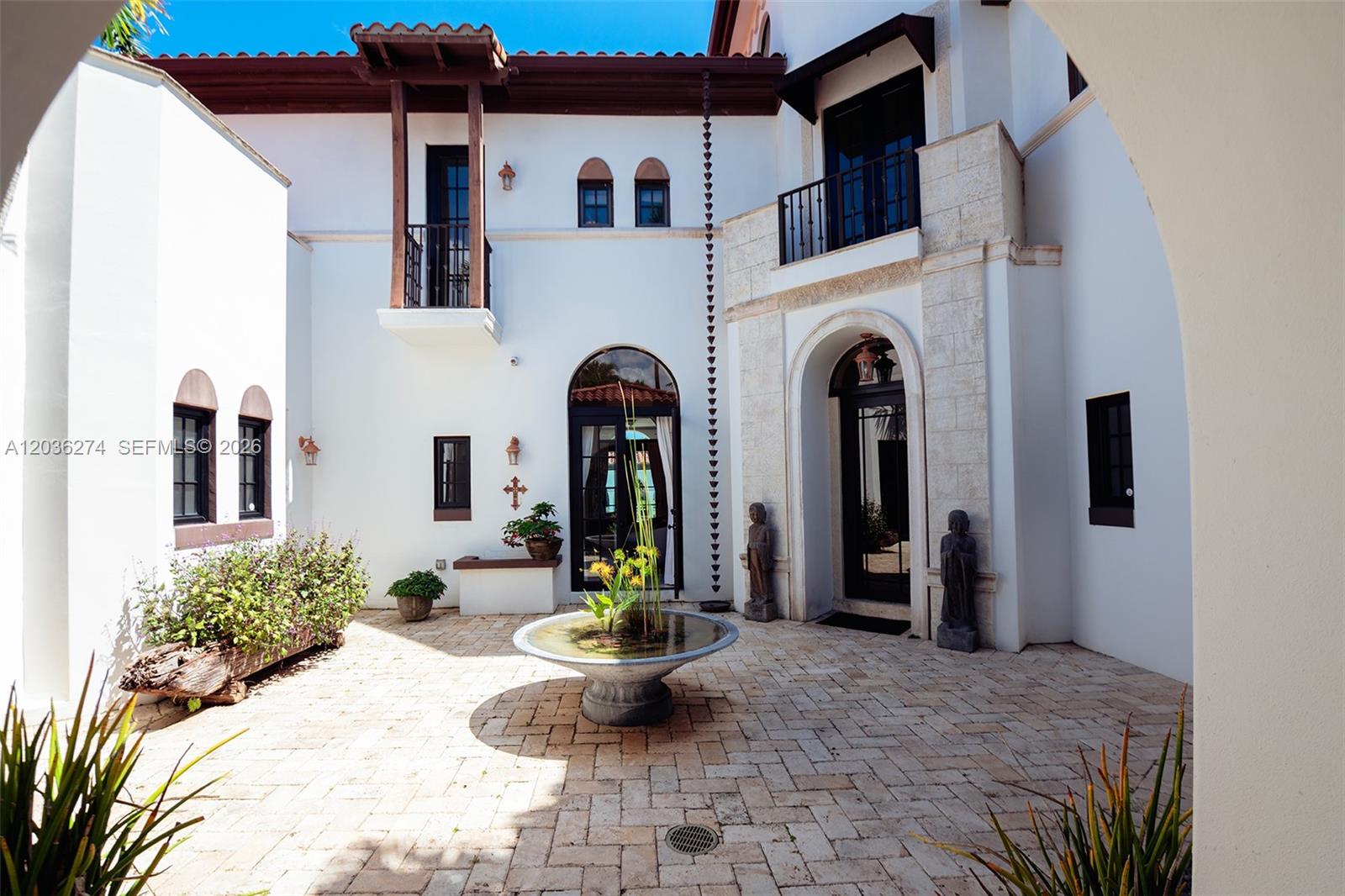 A courtyard features a stone fountain, paved patio, and white stucco walls with arched doorways — 6220 SW 86th St # 0, Miami FL 33143, MIAMI, FL