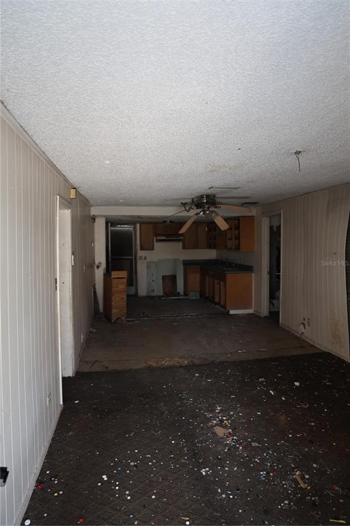 An interior view shows a kitchen and living area with wood-paneled walls and debris-covered floors — 232 C STREET, LAKE WALES, FL