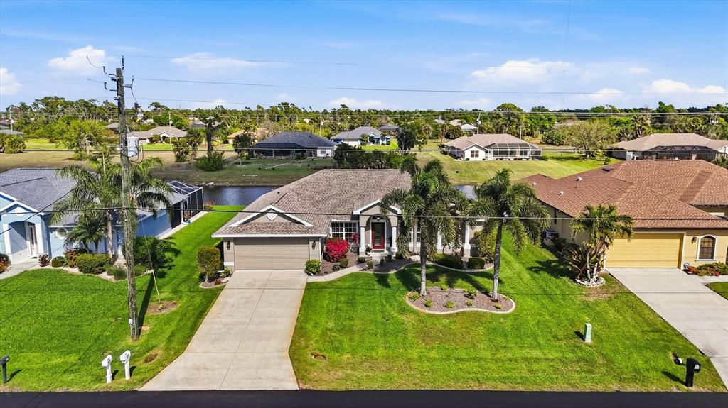 An aerial view shows a single-story house with a tan exterior, garage, and palm trees — 827 ROTONDA CIRCLE, ROTONDA WEST, FL