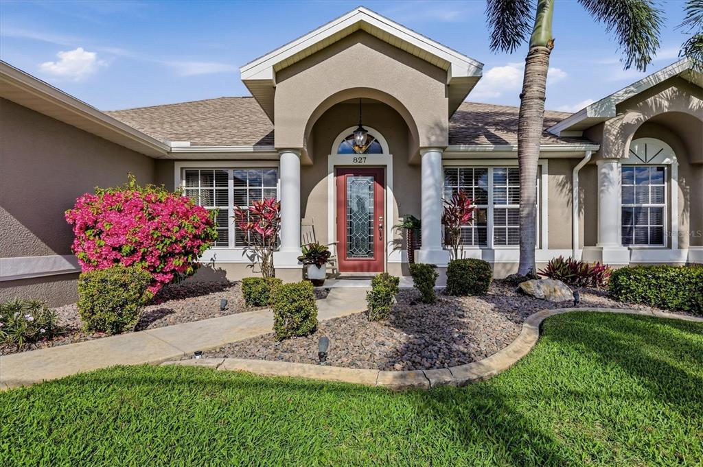 The exterior of a single-story house features a covered entryway with columns and landscaping — 827 ROTONDA CIRCLE, ROTONDA WEST, FL