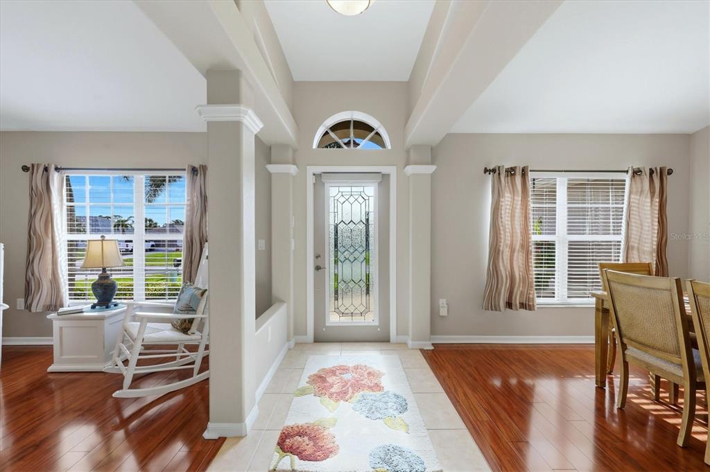 An entryway with a glass-paneled front door, tile flooring, and hardwood floors in adjacent rooms — 827 ROTONDA CIRCLE, ROTONDA WEST, FL