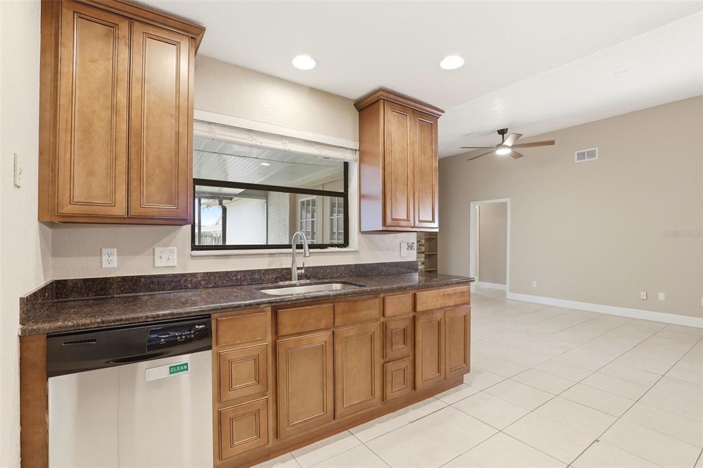 A kitchen with wood cabinets, dark countertops, a dishwasher, and tile flooring — 7320 WETHERSFIELD DRIVE, ORLANDO, FL