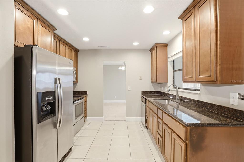 A kitchen features stainless steel appliances, dark granite countertops, and wood cabinets — 7320 WETHERSFIELD DRIVE, ORLANDO, FL