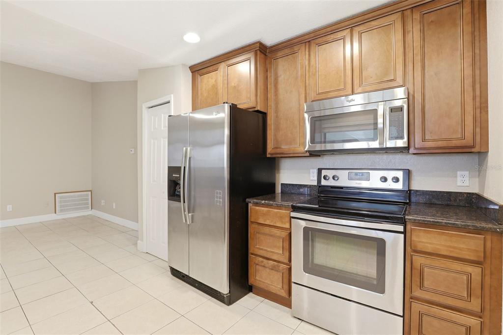 A kitchen featuring wood cabinets, stainless steel appliances, and tile flooring — 7320 WETHERSFIELD DRIVE, ORLANDO, FL