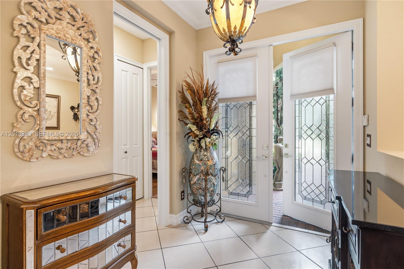 An entryway features a mirrored chest, a decorative vase with dried plants, and glass-paned doors — 5574 49th Ave, Vero Beach FL 32967, VERO BEACH, FL