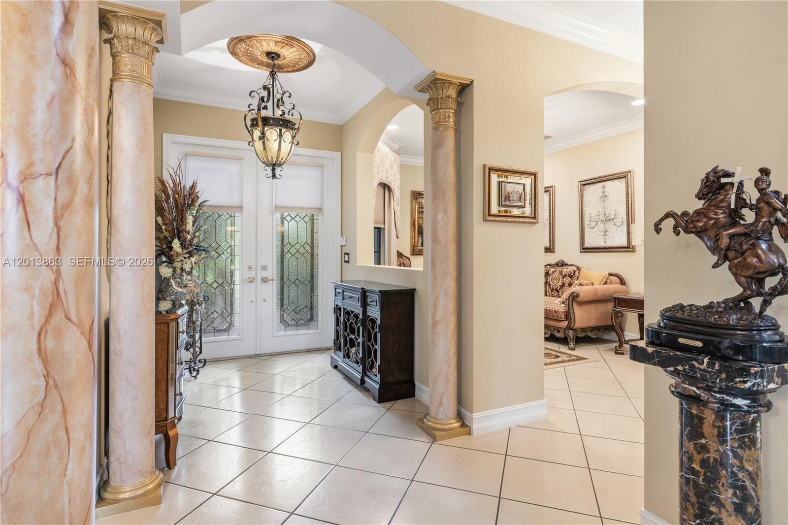 An entryway features tiled floors, decorative columns, a chandelier, and a bronze equestrian statue — 5574 49th Ave, Vero Beach FL 32967, VERO BEACH, FL