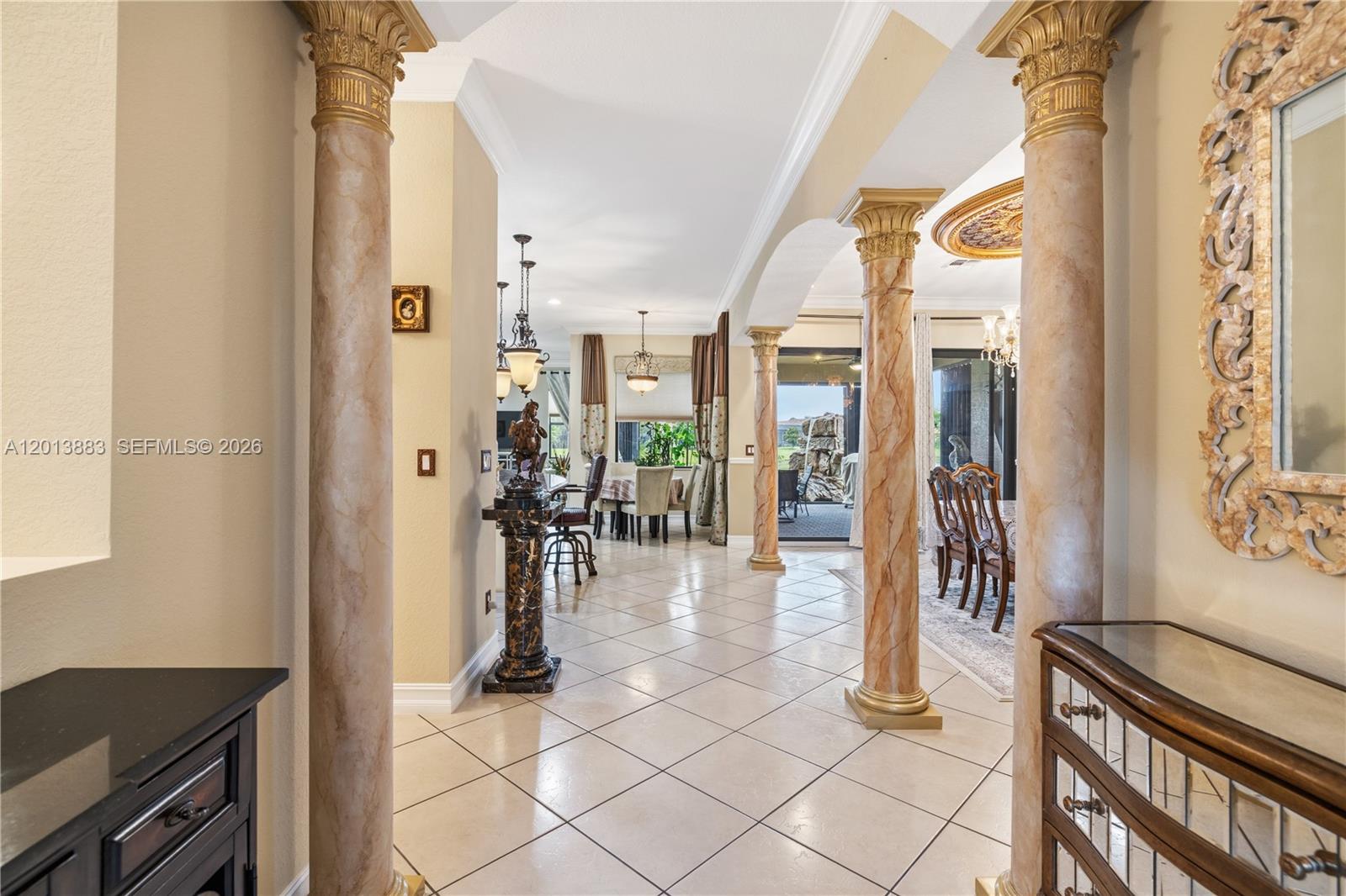 A tiled hallway features decorative columns leading to a dining area and a patio view — 5574 49th Ave, Vero Beach FL 32967, VERO BEACH, FL