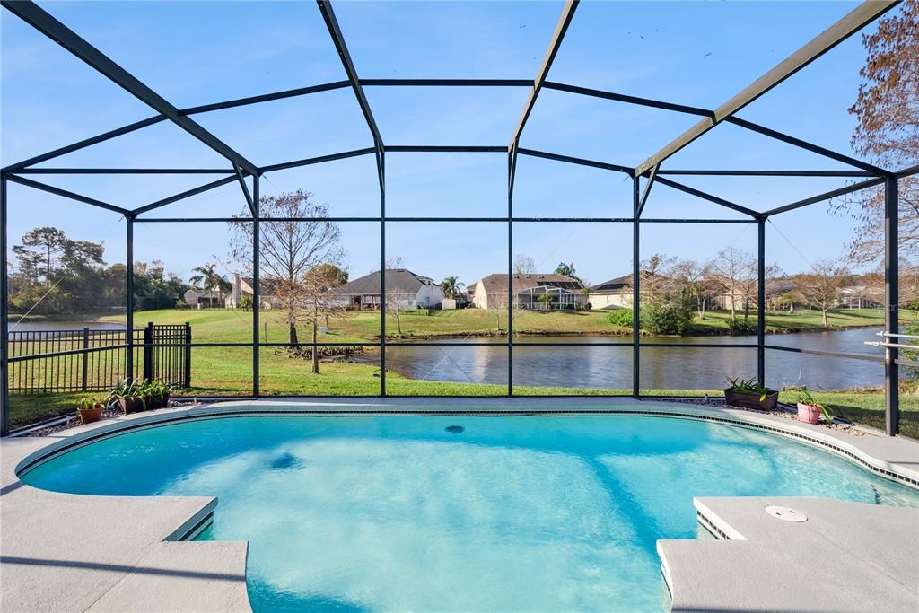 A screened-in swimming pool overlooks a lake and neighboring houses on a sunny day — 639 LAKEHAVEN CIRCLE, ORLANDO, FL