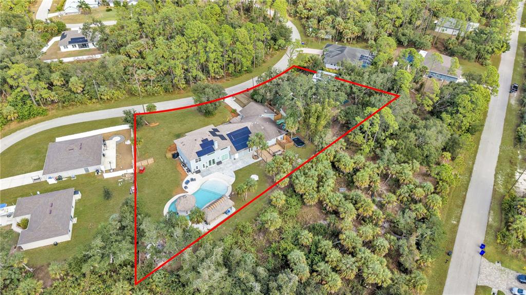 An aerial view shows a house with a pool and solar panels on a lot — 3694 CRANDON ROAD, NORTH PORT, FL