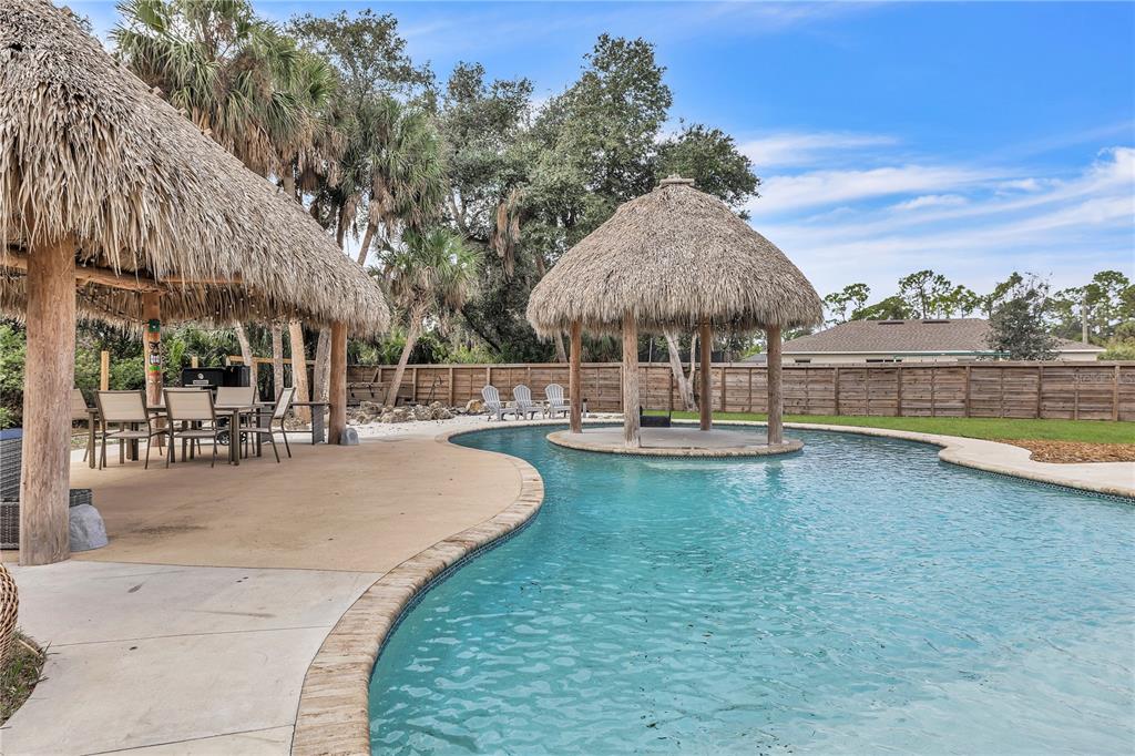 A backyard swimming pool features a tiki hut island and a covered patio area — 3694 CRANDON ROAD, NORTH PORT, FL