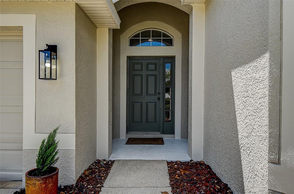 A front entryway features a dark gray door with a sidelight and arched transom window — 16730 FAIRBOLT WAY, ODESSA, FL