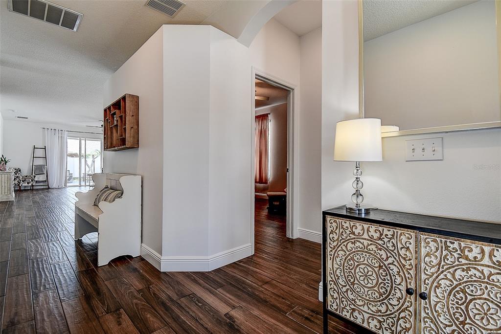 An entryway features dark wood-look tile flooring, a decorative cabinet, and a white bench — 16730 FAIRBOLT WAY, ODESSA, FL