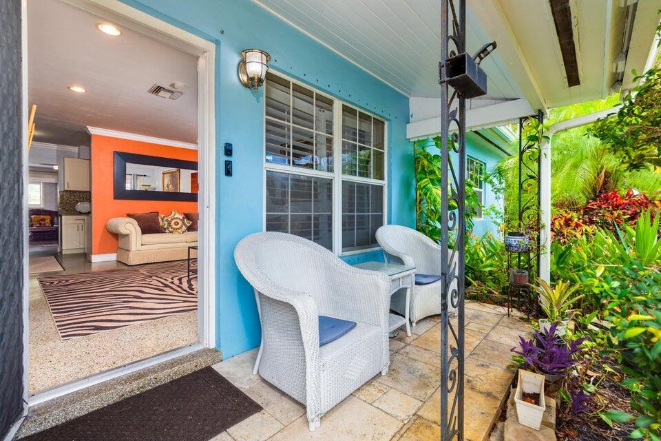 A view from a blue-walled porch with white wicker chairs into a living room — 145 SE 3rd Avenue, Boynton Beach FL 33435, BOYNTON BEACH, FL