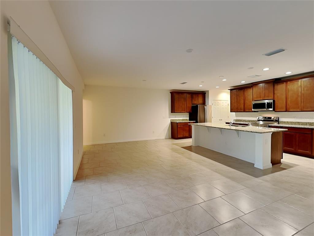 An open-concept kitchen features dark wood cabinets, granite countertops, and a large central island — 1615 CLOUDY COURT, ST CLOUD, FL