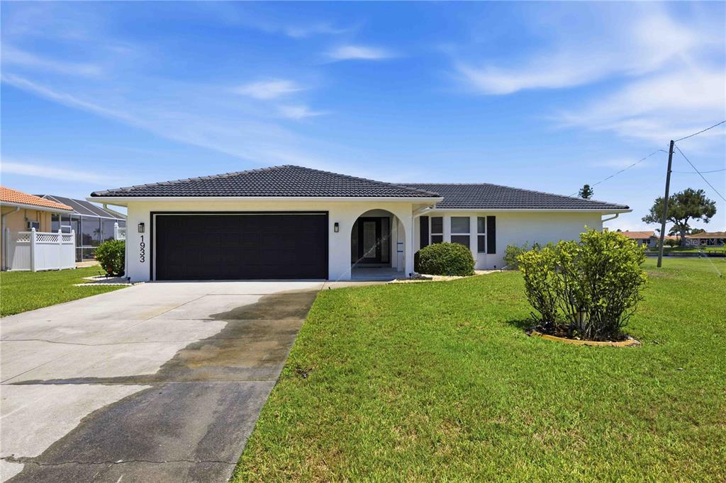 A single-story house with a white exterior, dark roof, and a two-car garage — 1933 FAIRVIEW DRIVE, ENGLEWOOD, FL