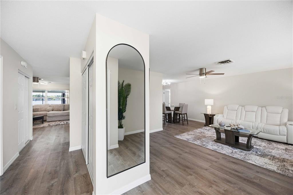 A living room with wood-look flooring, a white sofa, and an arched wall mirror — 1933 FAIRVIEW DRIVE, ENGLEWOOD, FL