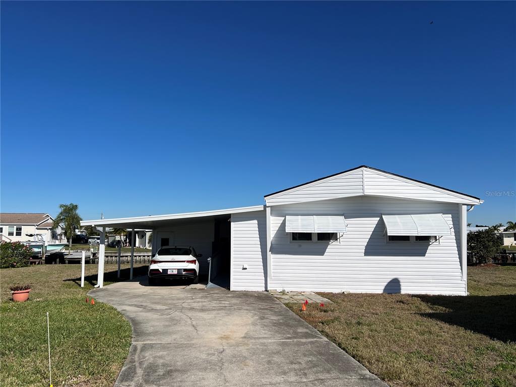 A white single-story house with a carport and a concrete driveway under a clear sky — 217 MOUNT ISLE AVENUE NE UNIT 197, ST PETERSBURG, FL