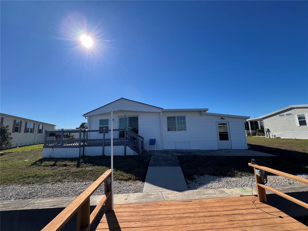 A white mobile home features a wooden deck, a concrete walkway, and a clear sky — 217 MOUNT ISLE AVENUE NE UNIT 197, ST PETERSBURG, FL