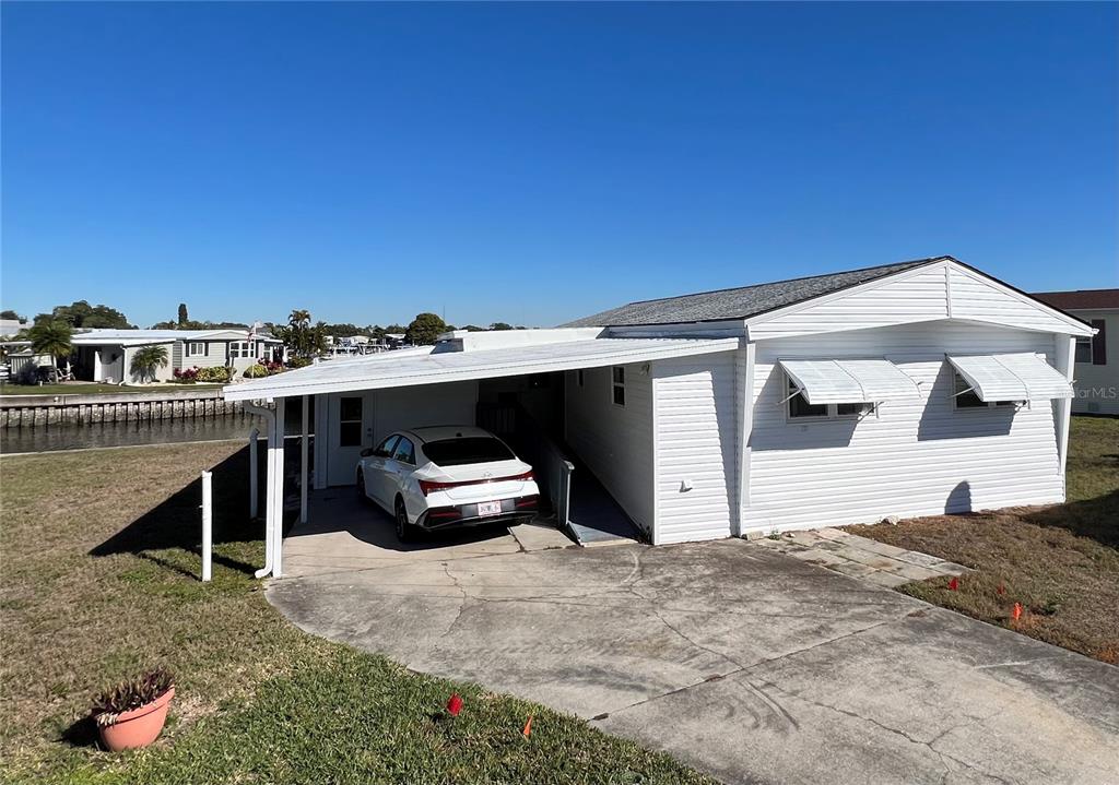 A white mobile home features a carport, a concrete driveway, and a canal-side location — 217 MOUNT ISLE AVENUE NE UNIT 197, ST PETERSBURG, FL