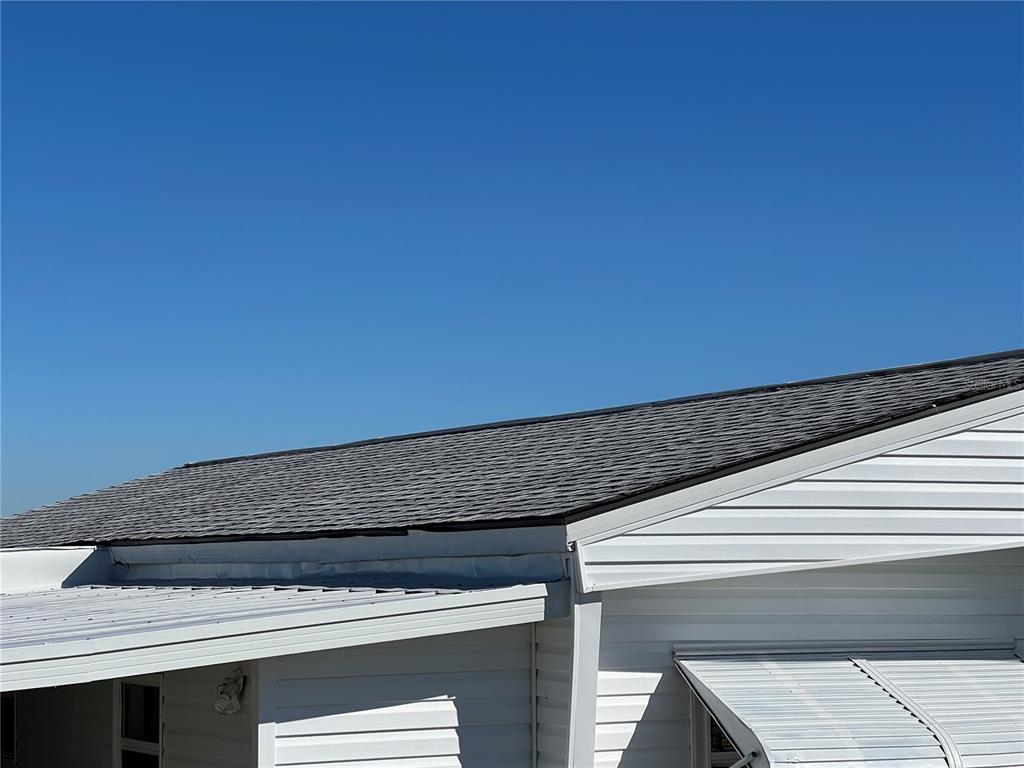 A view of a shingled roof and white siding on the exterior of a home — 217 MOUNT ISLE AVENUE NE UNIT 197, ST PETERSBURG, FL