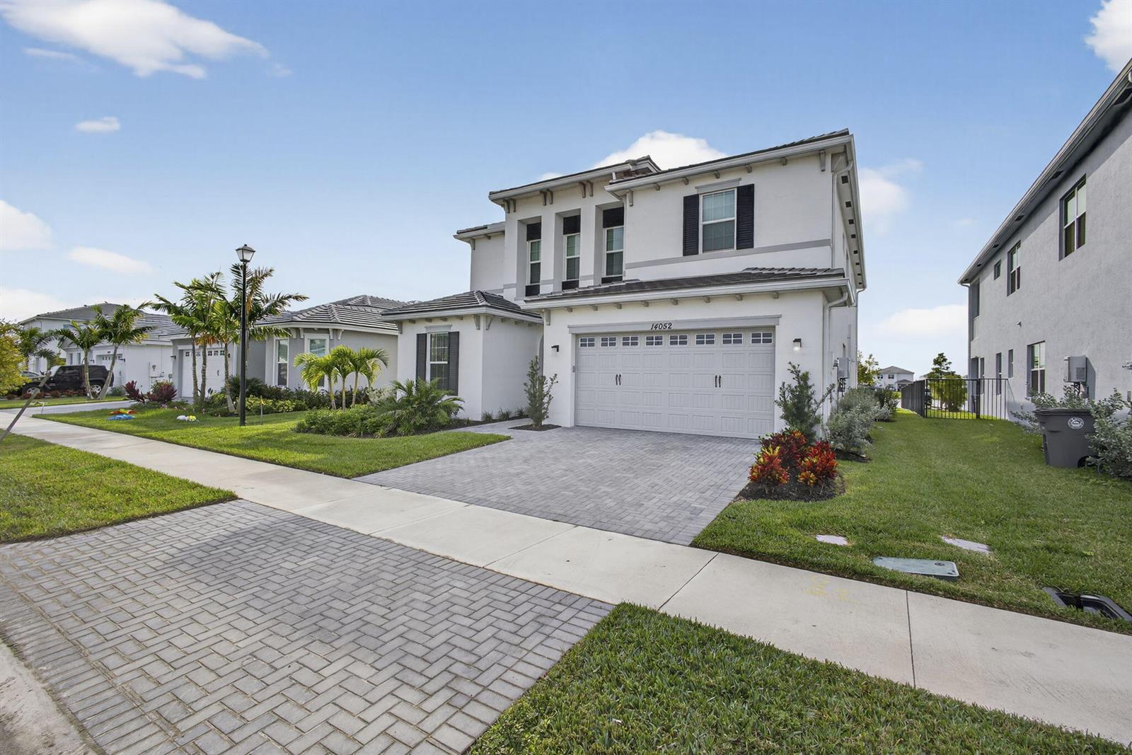 A two-story white stucco house with a paved driveway and a two-car garage — 14052 Spruce Pine Drive, FL 33470, FL