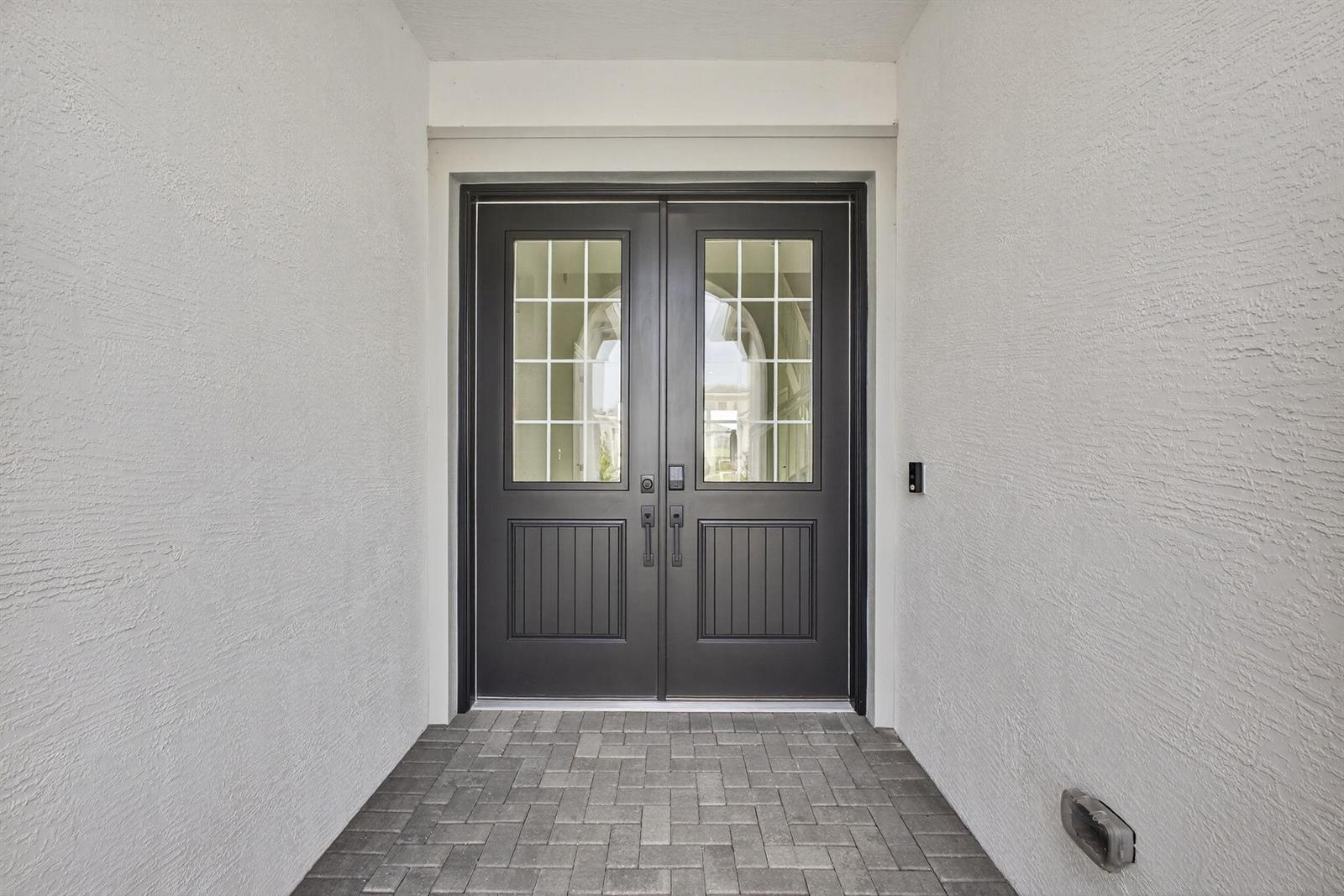 A dark double front door with glass panes is set within a white stucco entryway — 14052 Spruce Pine Drive, FL 33470, FL