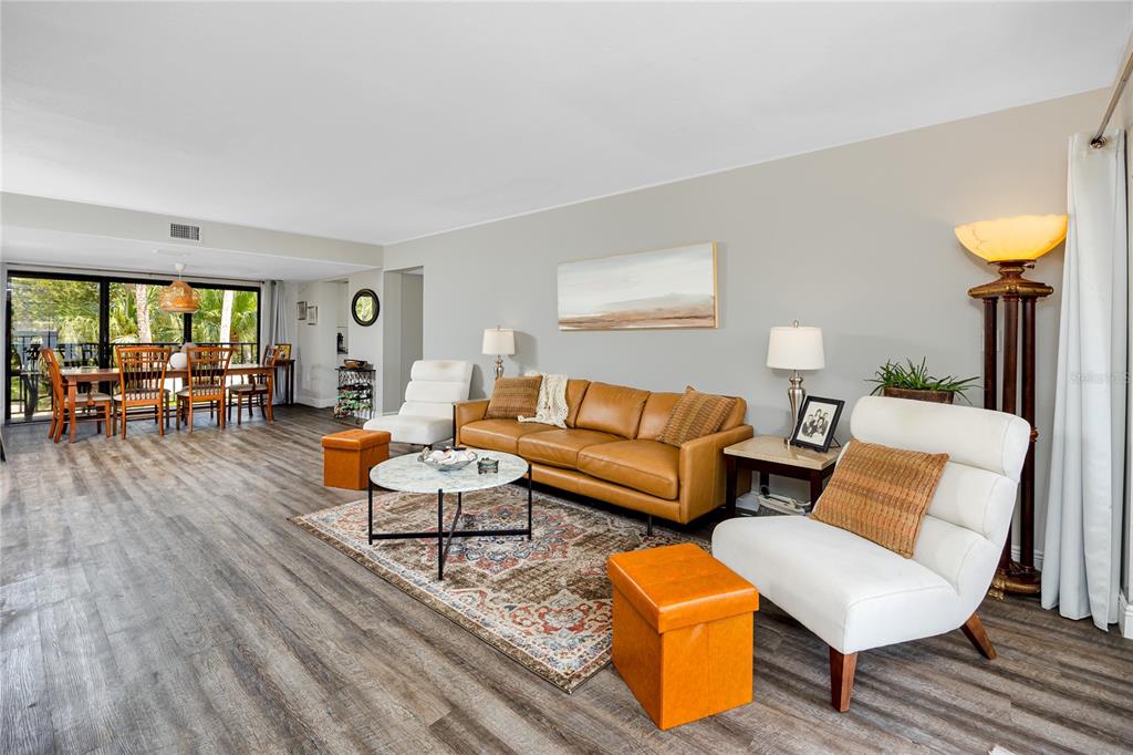 A living room features a leather sofa, two white chairs, and wood-look flooring — 7530 SUNSHINE SKYWAY LANE S UNIT 115, ST PETERSBURG, FL