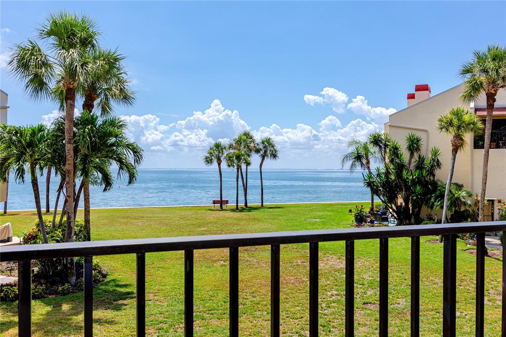 A view of a grassy lawn, palm trees, and the ocean from a balcony — 7530 SUNSHINE SKYWAY LANE S UNIT 115, ST PETERSBURG, FL