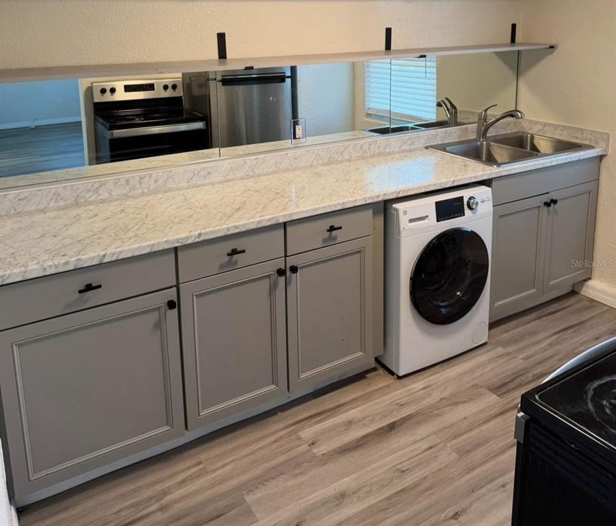 A kitchen features gray cabinets, marble-look countertops, a built-in washing machine, and a mirrored backsplash — 2219 HELEN AVENUE, ORLANDO, FL