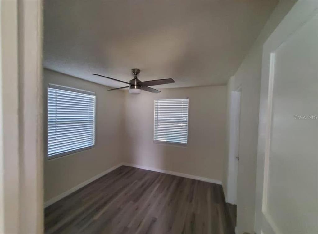 An empty bedroom features light-colored walls, wood-look flooring, two windows with blinds, and a ceiling fan — 2219 HELEN AVENUE, ORLANDO, FL