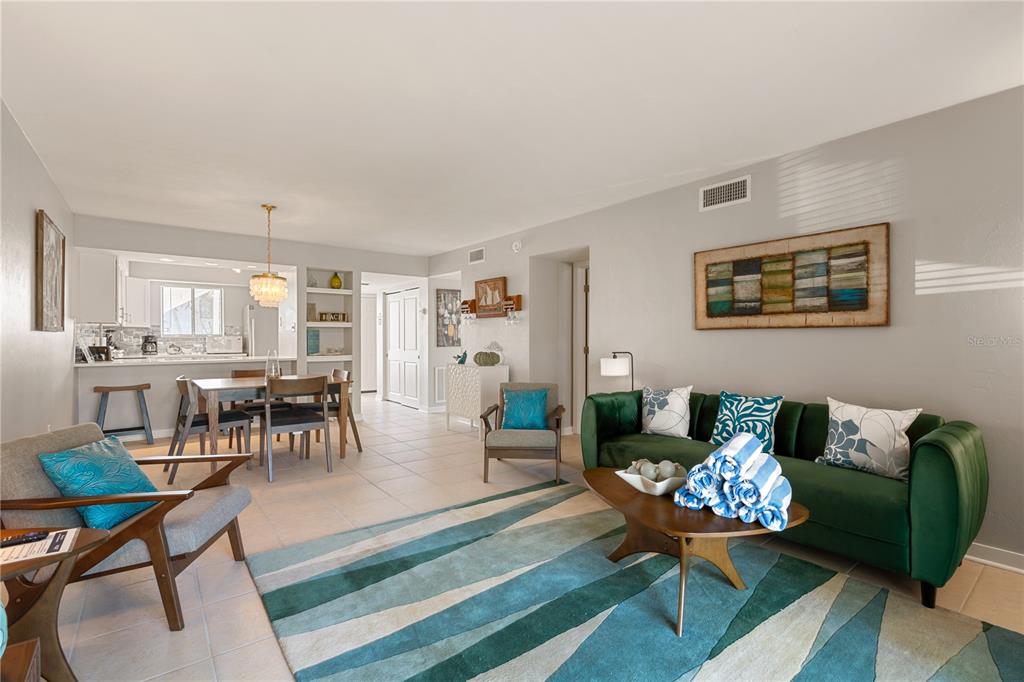 A living room and dining area with tile floors, a green sofa, and blue accents — 1801 GULF DRIVE N UNIT 148, BRADENTON BEACH, FL