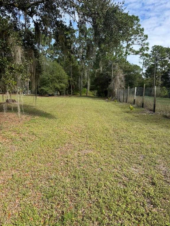 A grassy, open lot is bordered by trees and a chain-link fence — 415 N VERDA STREET, CLEWISTON, FL