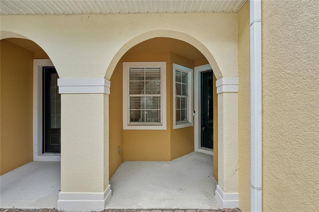A covered entryway features two arched openings, stucco walls, and a dark front door — 5080 CYPRESS BRANCH POINT, OVIEDO, FL