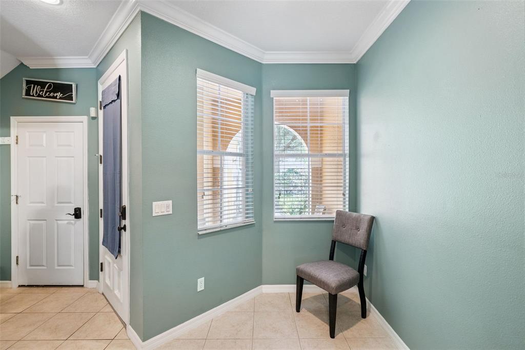 An entryway features light blue walls, tile flooring, two windows with blinds, and a gray chair — 5080 CYPRESS BRANCH POINT, OVIEDO, FL