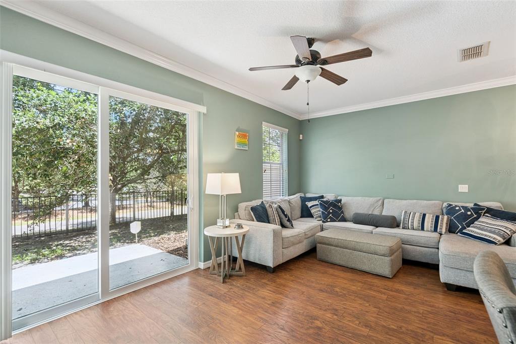 A living room with sage green walls, a sectional sofa, and a sliding glass door — 5080 CYPRESS BRANCH POINT, OVIEDO, FL
