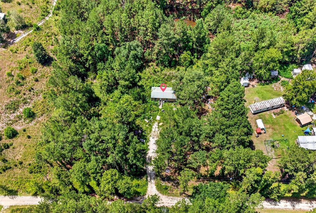 An aerial view shows a house nestled in a wooded lot with a dirt driveway — 7320 NE 137TH PLACE, CITRA, FL