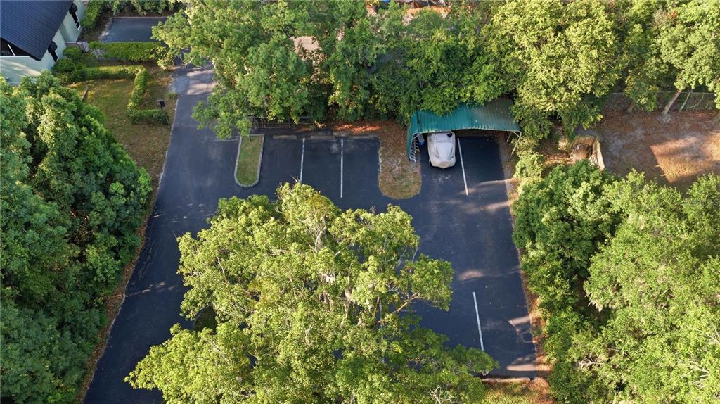 An aerial view shows a paved parking lot with a covered carport nestled among trees — TBD NE 3RD STREET, OCALA, FL