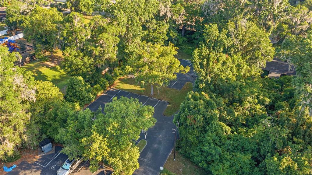 An aerial view shows a paved parking lot surrounded by dense trees and a playground — TBD NE 3RD STREET, OCALA, FL