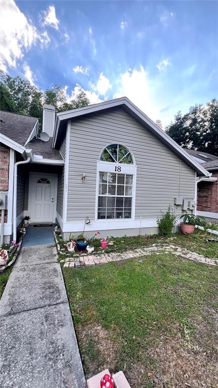 A gray-sided house exterior features a white front door and an arched window above — 5824 RED CEDAR LANE, TAMPA, FL