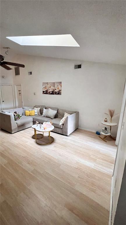 A living room features light wood-look flooring, a gray sectional sofa, and a ceiling skylight — 5824 RED CEDAR LANE, TAMPA, FL