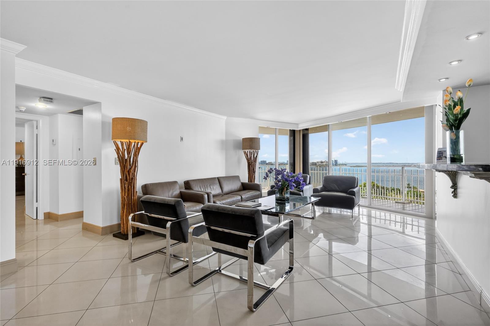 A living room with tile floors, leather seating, and a balcony overlooking the water — 4000 Towerside Ter # 1612, Miami FL 33138, MIAMI, FL
