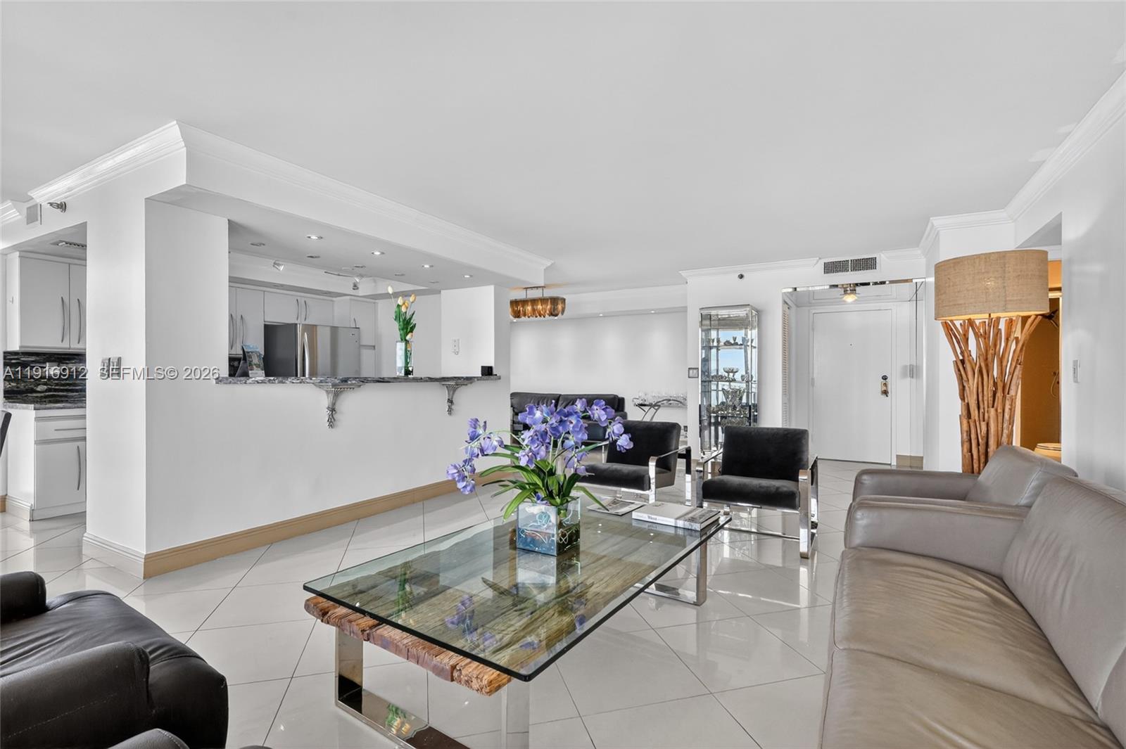 A living room with white tile floors, a glass coffee table, and an open kitchen — 4000 Towerside Ter # 1612, Miami FL 33138, MIAMI, FL